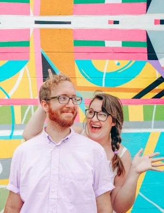 Couple being silly against a brightly colored graffiti background.